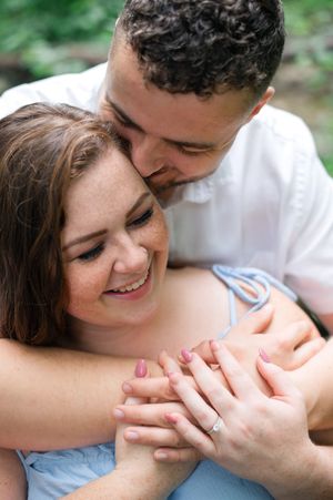 A tender romantic moment captured outdoors as a couple embraces and shares joyful laughter together.