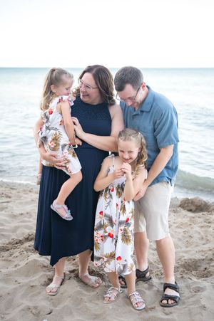 Family shares tender moments together on a sandy beach during a summer photo session.