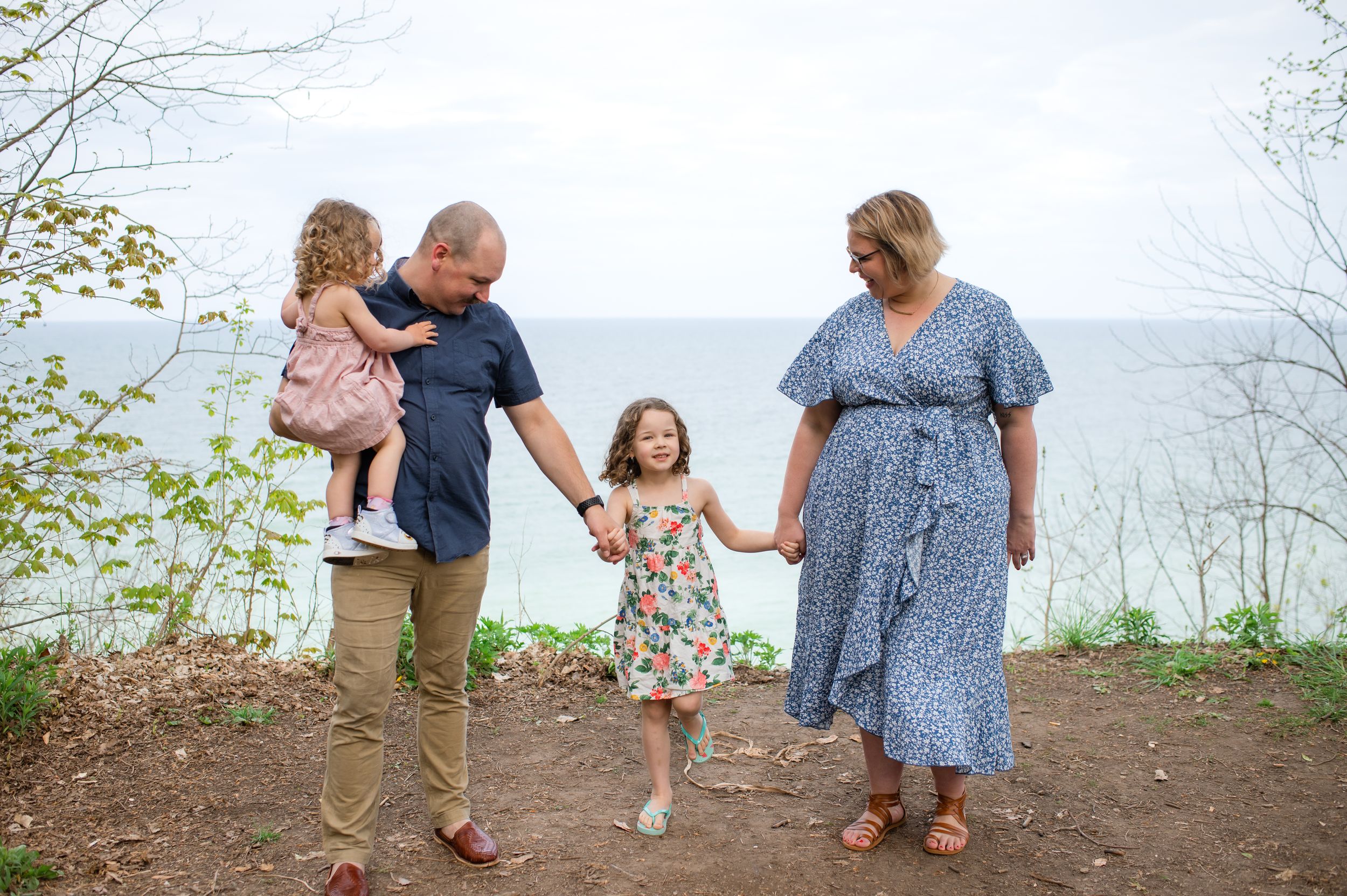 A family holds hands while walking together on a nature path during a sunny afternoon.