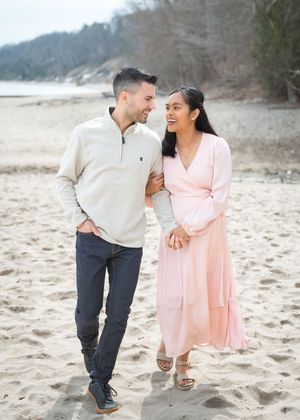 A couple shares joyful moments together during a romantic beach photoshoot in casual attire.