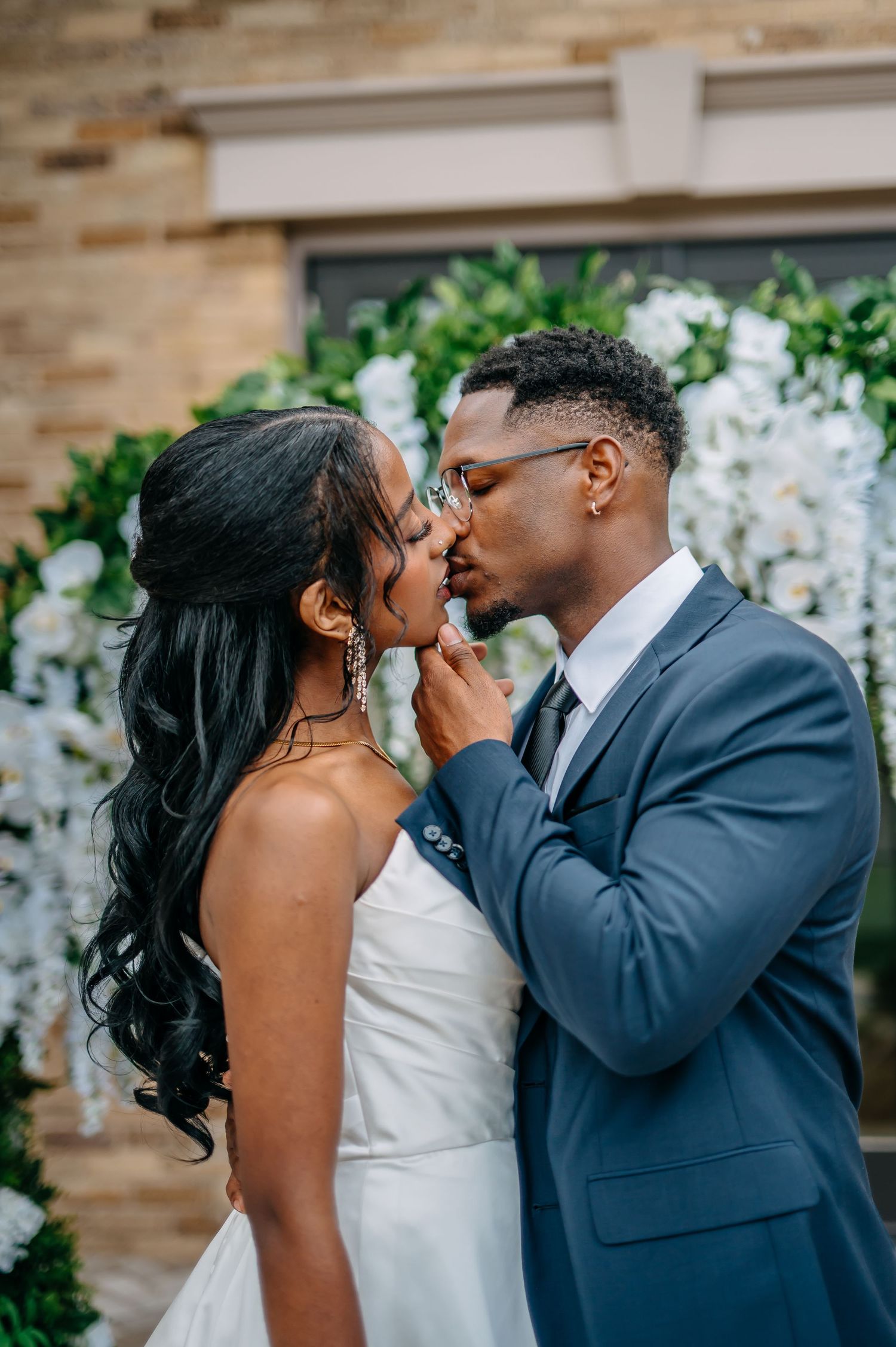 A romantic wedding couple shares tender kisses in a series of intimate portraits against a light-colored wall.