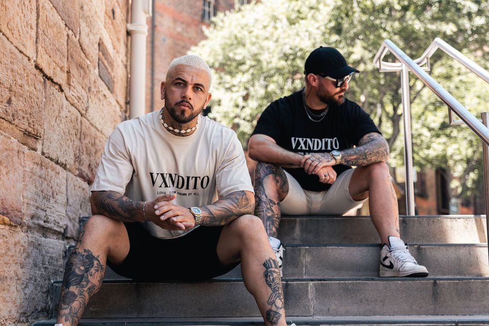 Urban fashion photoshoot showing streetwear clothing against brick wall backdrop.
