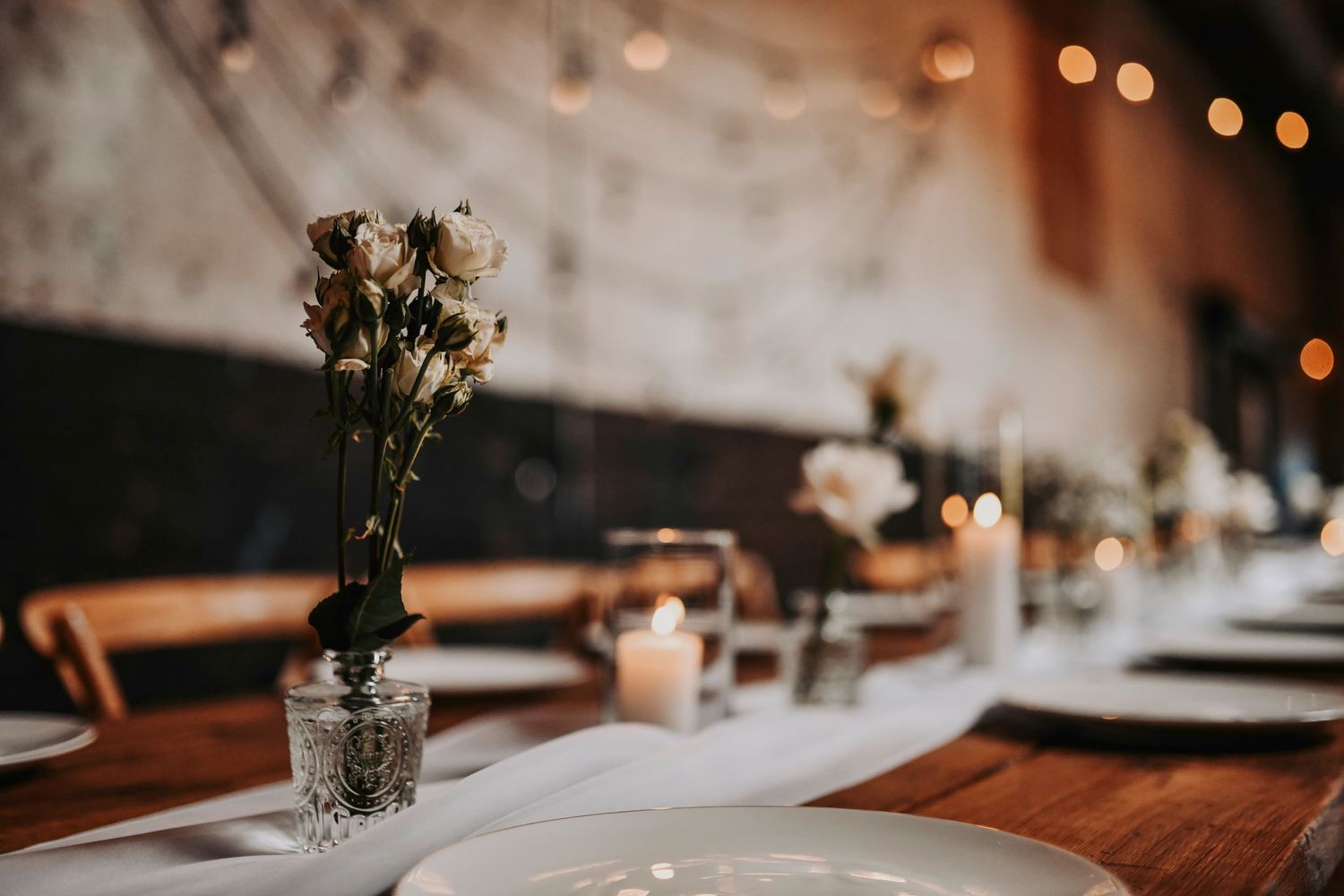 Reception tablescape featuring farm tables, cross-back chairs, and romantic florals at Brake & Clutch Warehouse.