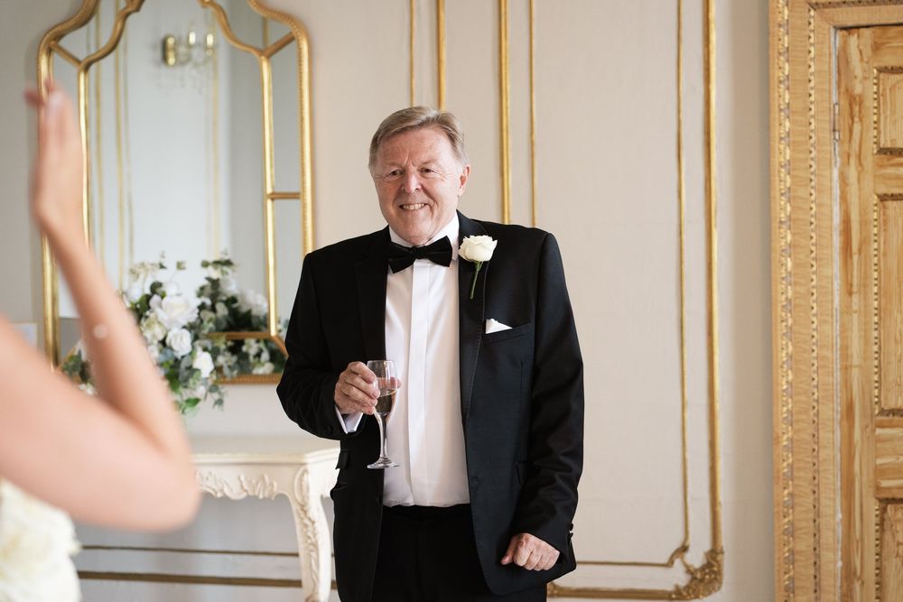 People in formal attire celebrate with champagne toasts in an elegant gold-trimmed ballroom.