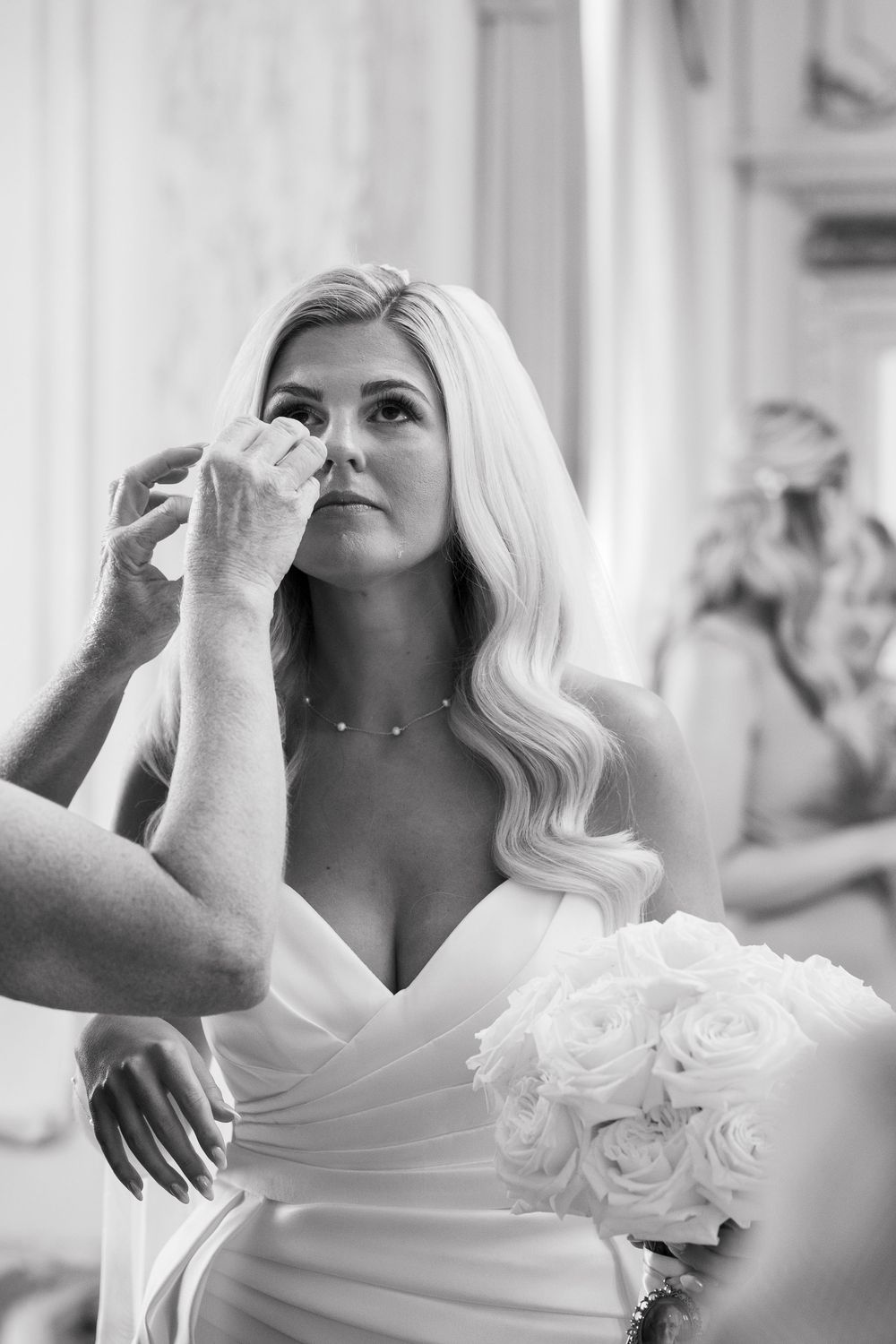 Black and white photo series showing emotional moments of a bride in a white dress with roses on her wedding day.