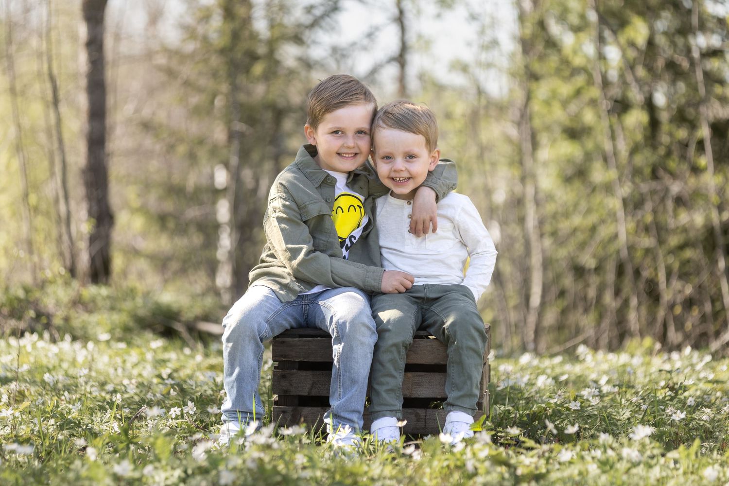 Syskonfotografering med två killar som sitter i ett hav av vitsippor