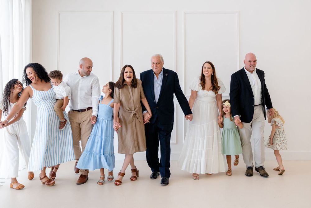 Family members sitting in a row against a white wall wearing coordinated casual outfits.
