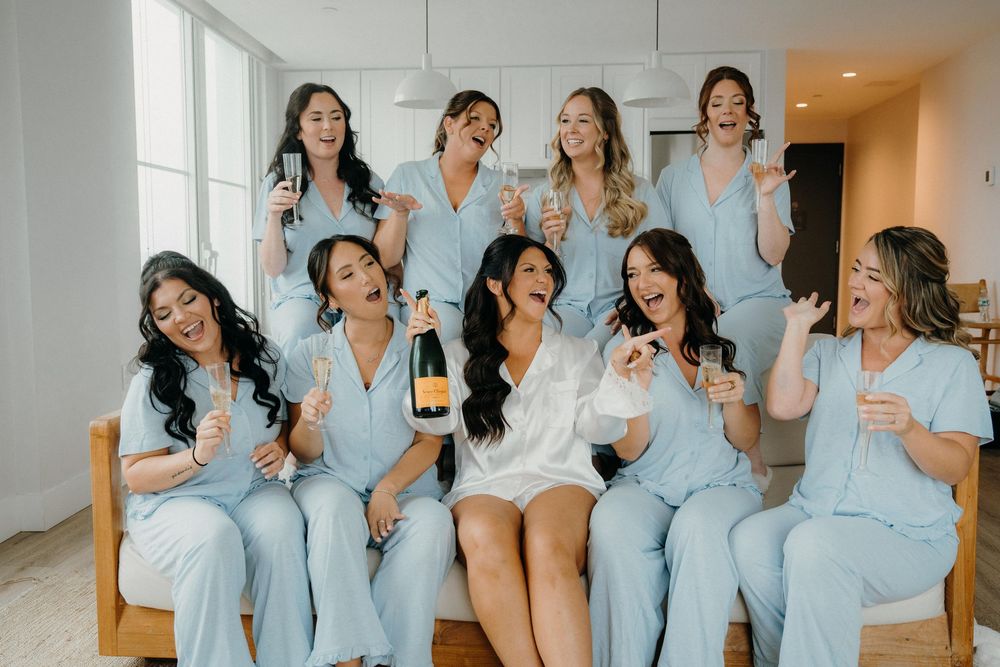 Group wearing matching light blue robes celebrate together with champagne glasses in a candid party moment.