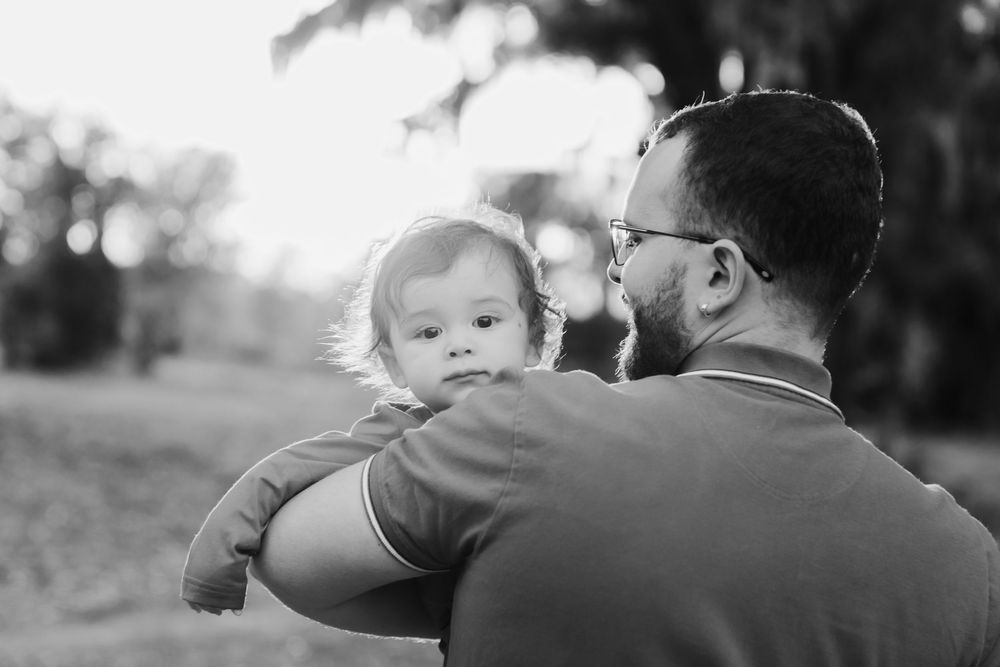 A series of black and white photographs showing tender moments between a parent and child outdoors.