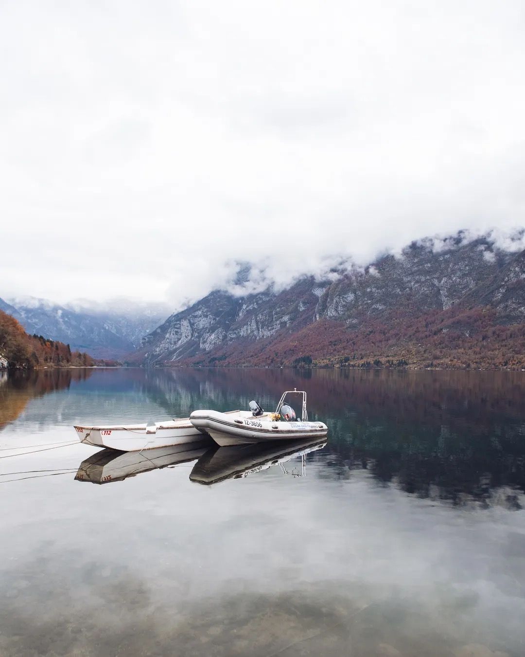 Canoe resting on a still mountain lake with mist and autumn colours reflecting in the water.