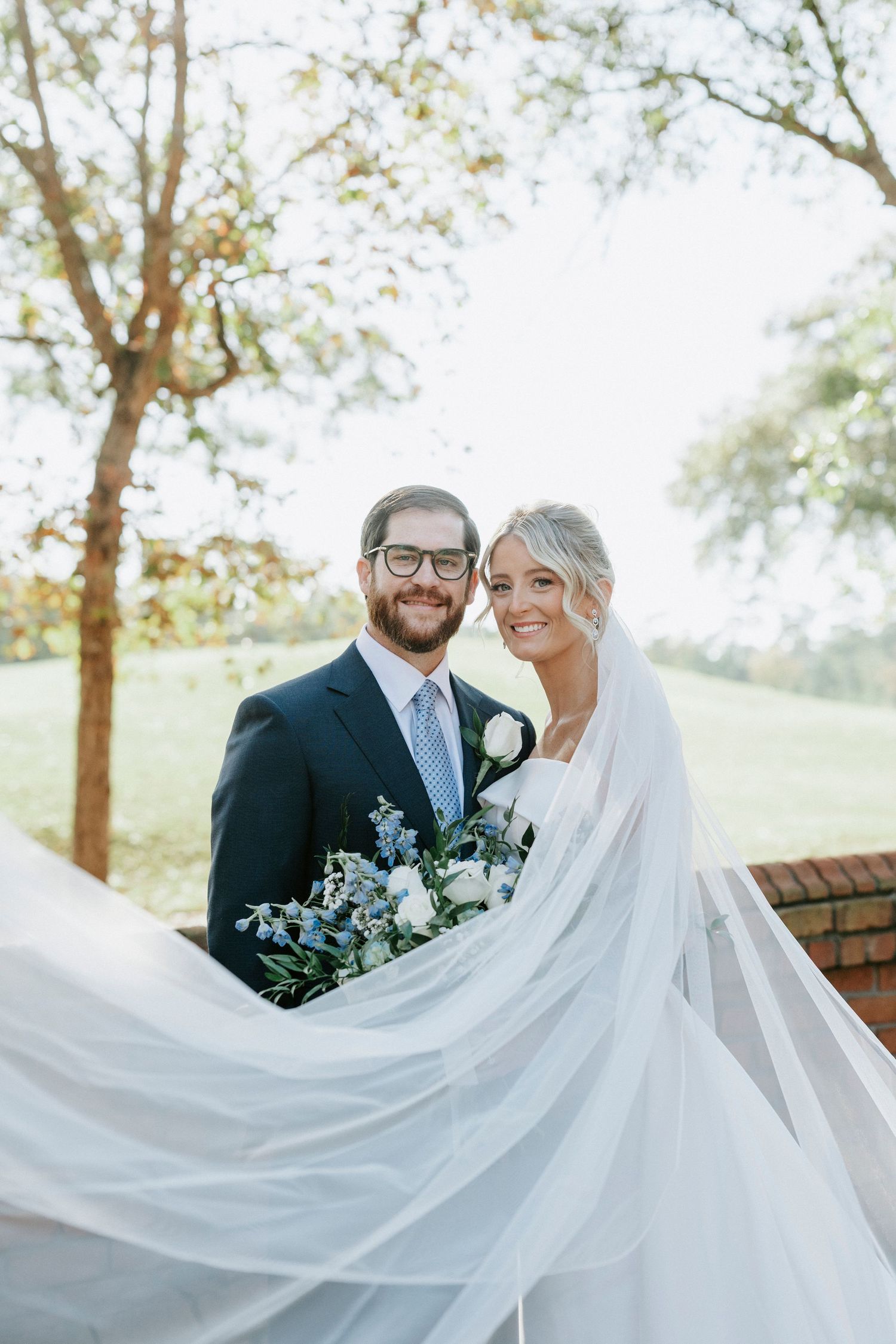 A joyful couple shares an intimate moment on their wedding day as the bride's veil flows elegantly in the breeze.