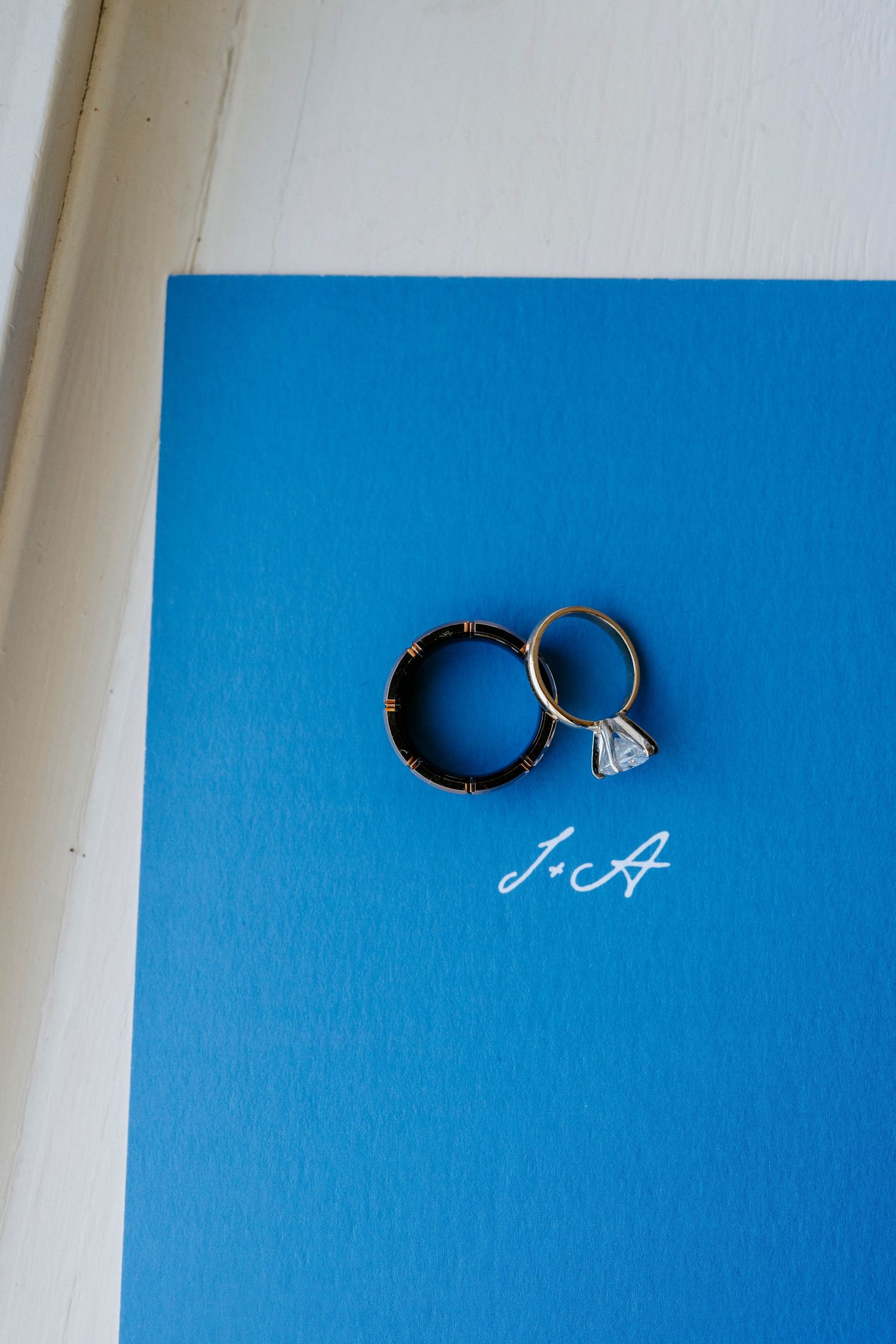 Two silver wedding rings casting shadows on a bright blue background in a creative minimalist composition.
