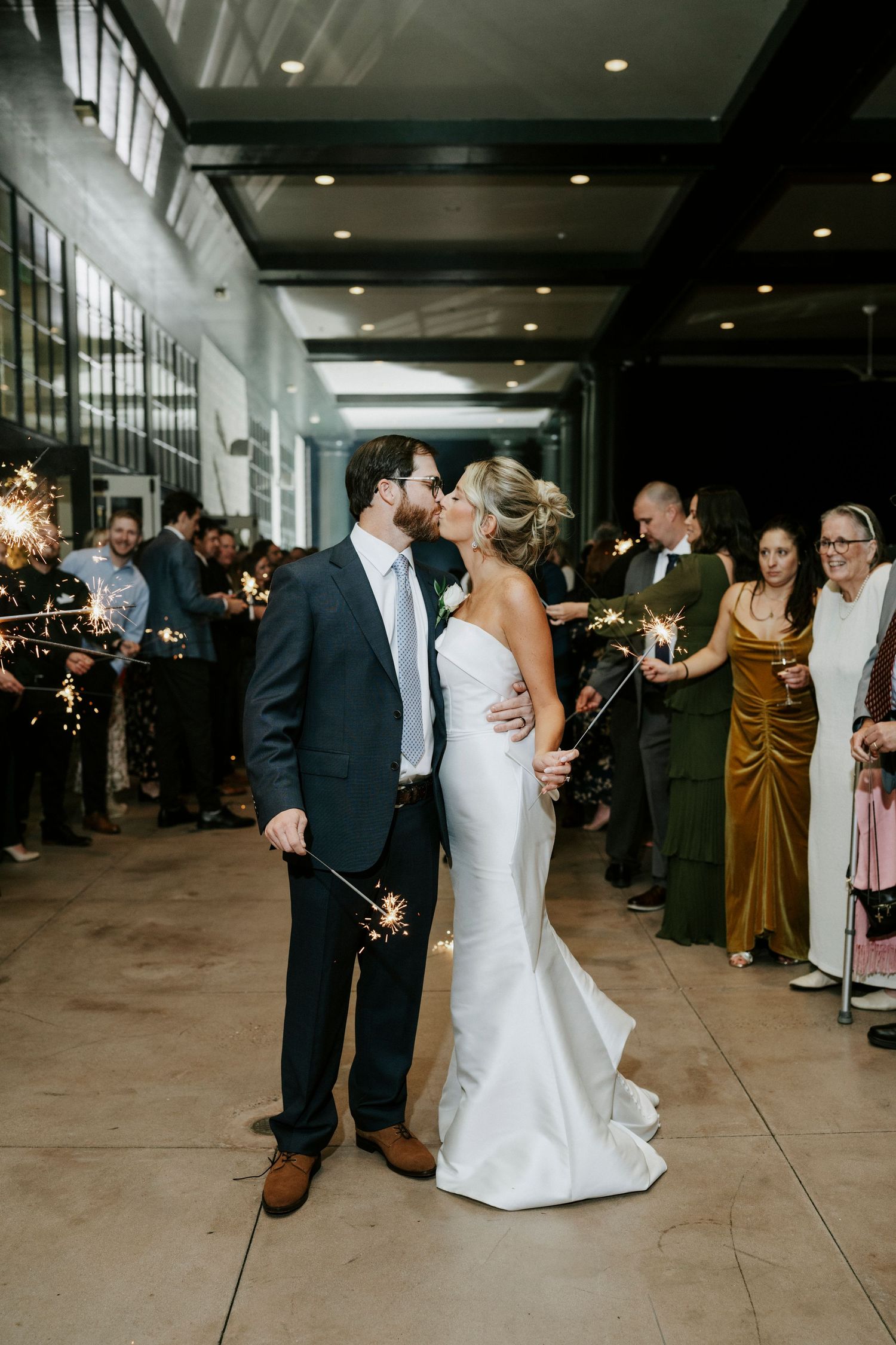Wedding celebration sparkler exit with guests lining pathway as couple dances through.