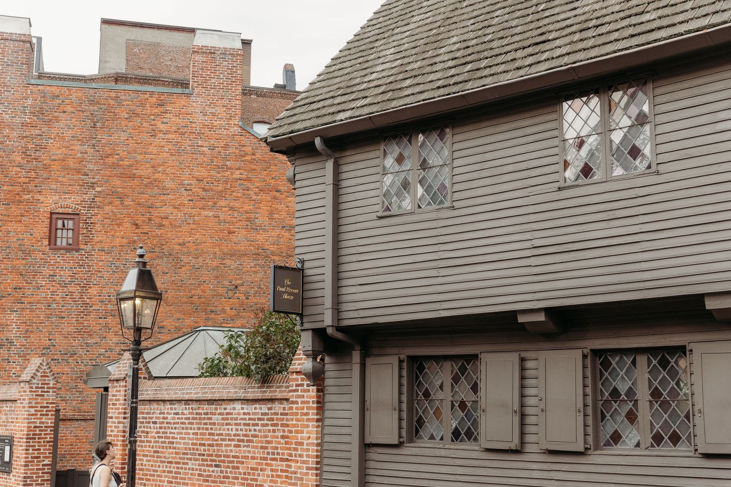 Historic brick and wooden buildings with diamond-paned windows line a street in Salem's colonial district.