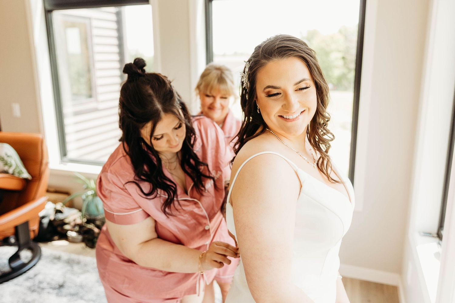 A group of women in pink robes celebrate together during a wedding morning preparation gathering.