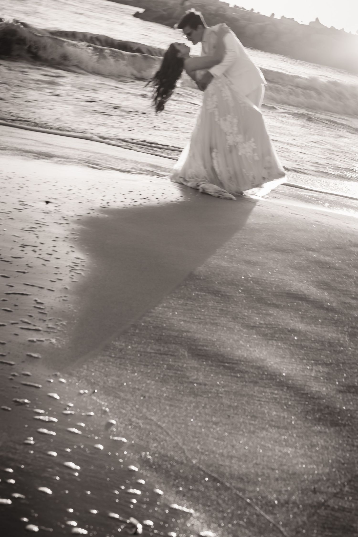 A couple embraces on a sandy beach during sunset in black and white wedding photography. Emotive Soulful wedding photography santa cruz ca