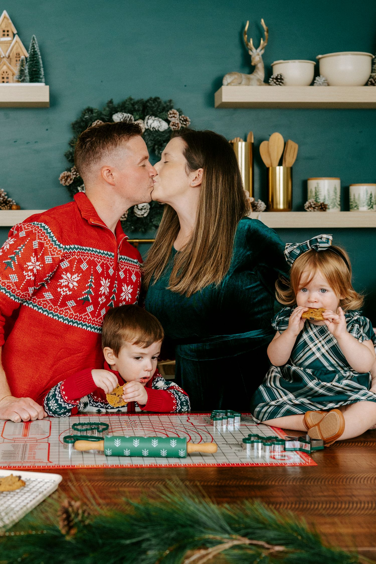 Family wearing festive holiday sweaters shares intimate moments at a rustic wooden table with Christmas decor.