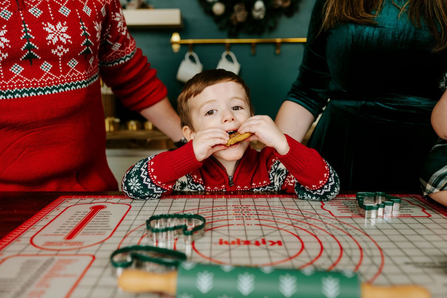 People wearing red holiday sweaters gather around a table for Christmas activities and crafts.
