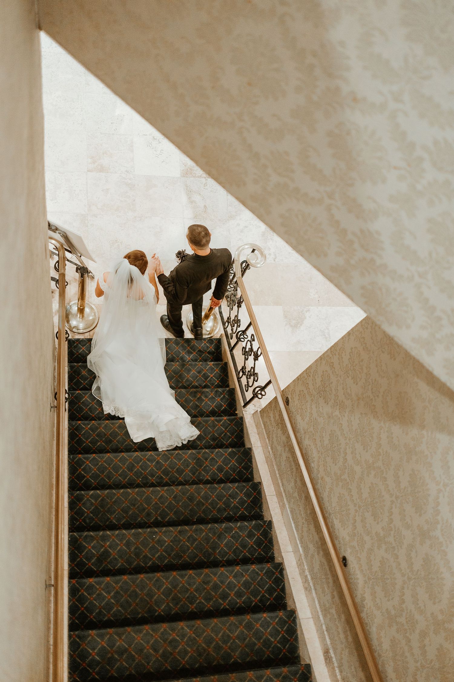 Wedding dress train cascades elegantly down carpeted staircase in artistic sequence.