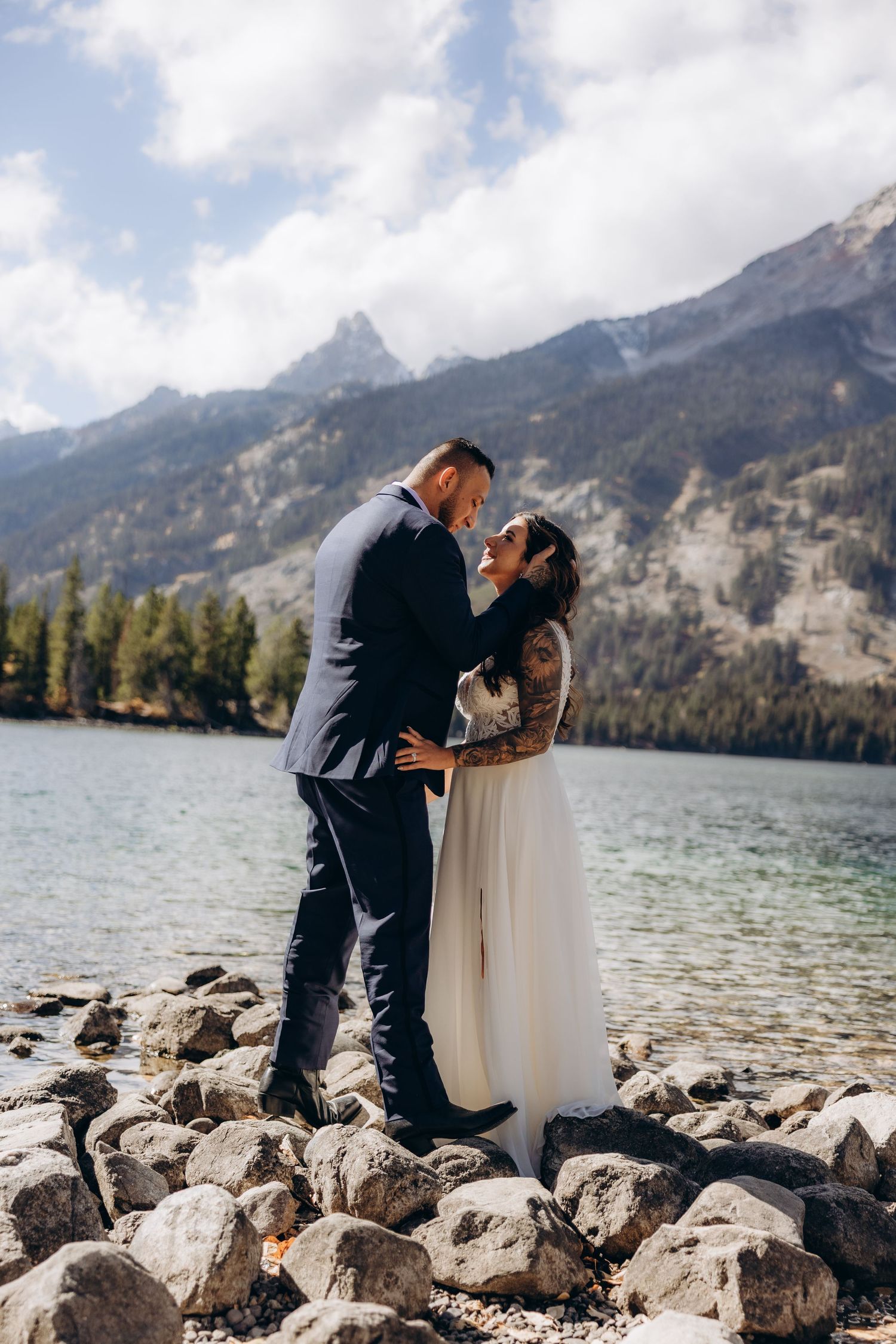 Couple celebrates their wedding day against a scenic mountain backdrop with sagebrush fields and dramatic clouds.