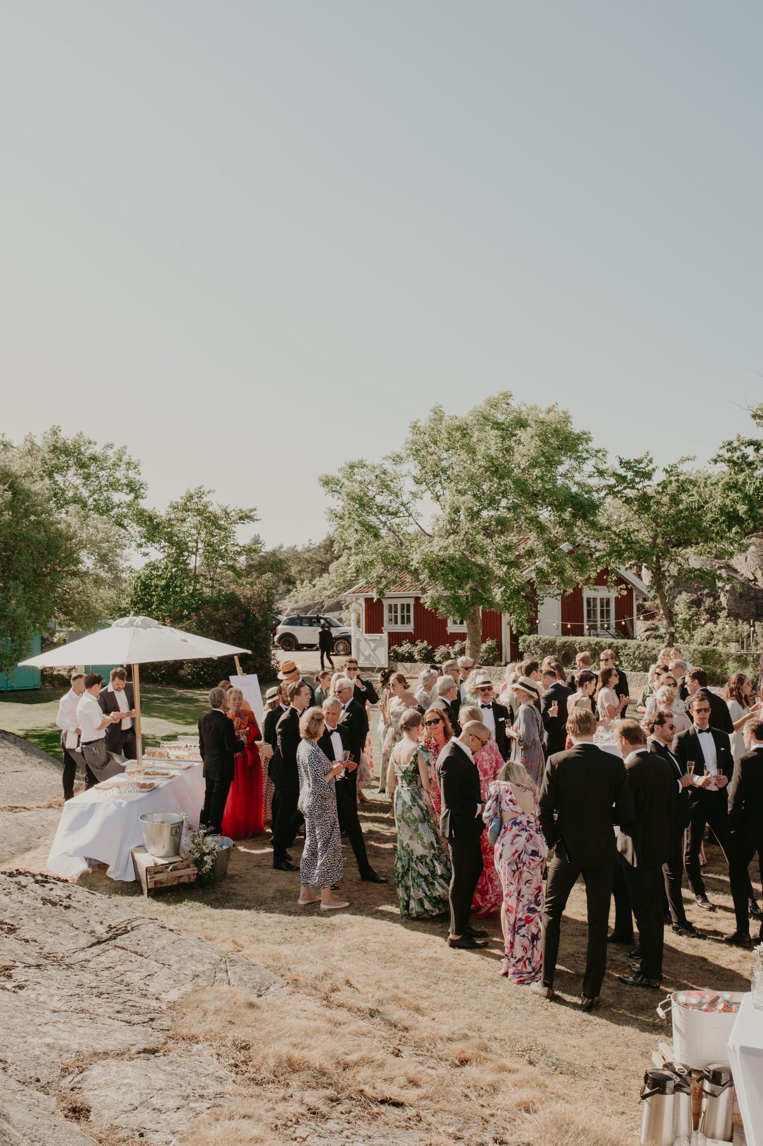Elegant wedding reception setup under white tent with wooden cross-back chairs and simple table settings.