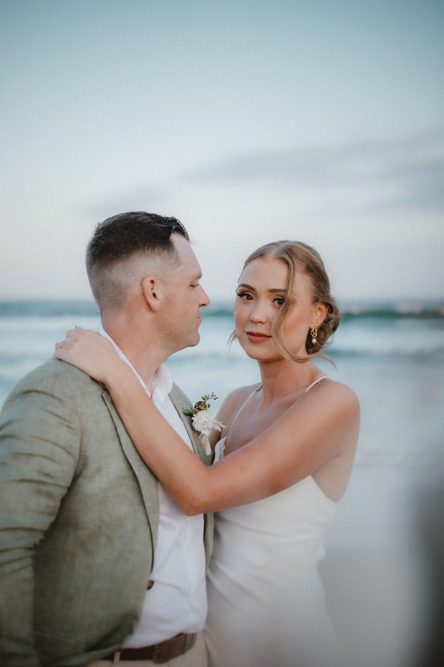 A couple shares an intimate moment against a waterfront backdrop at sunset.
