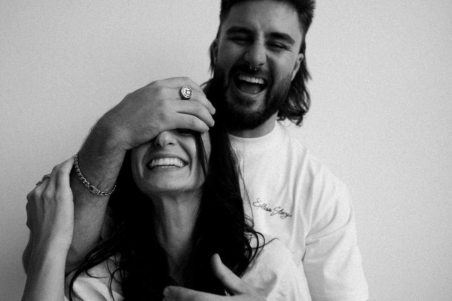 A candid black and white photo capturing a couple sharing a genuine laugh together.