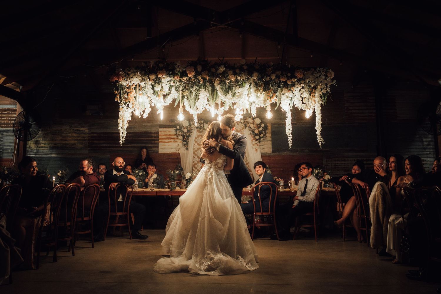 Wedding reception venue decorated with hanging lights and floral arrangements creating a magical atmosphere.