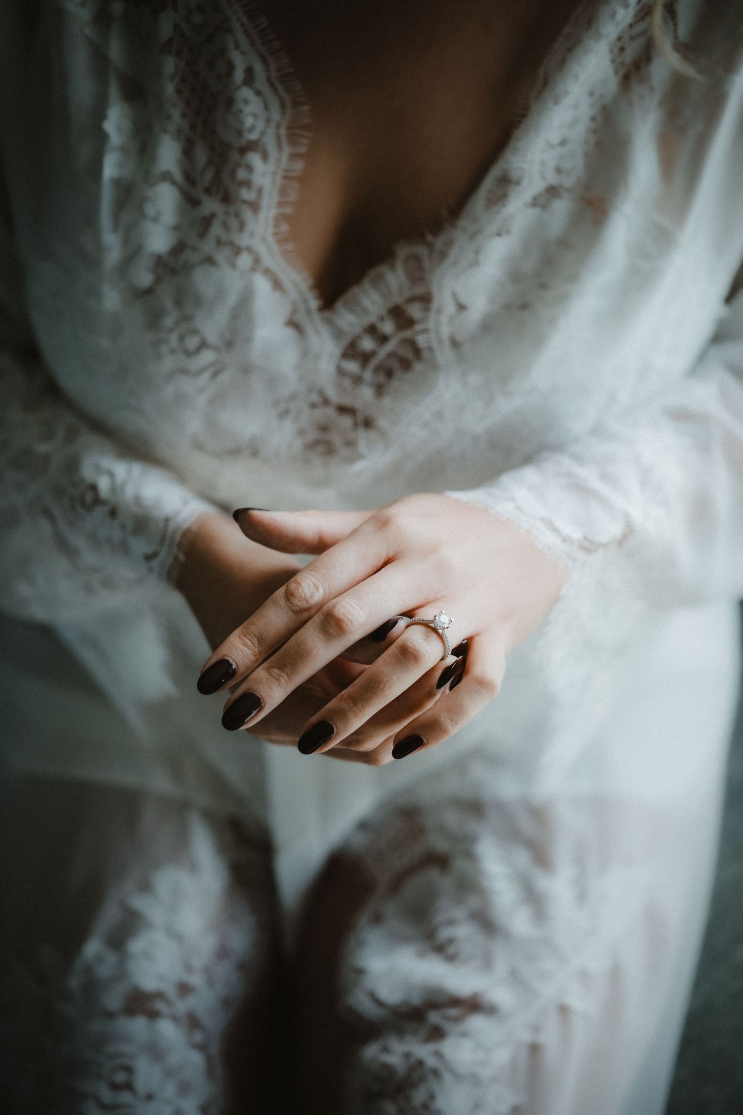 Close-up detail shot of a wedding ring on a lace dress.