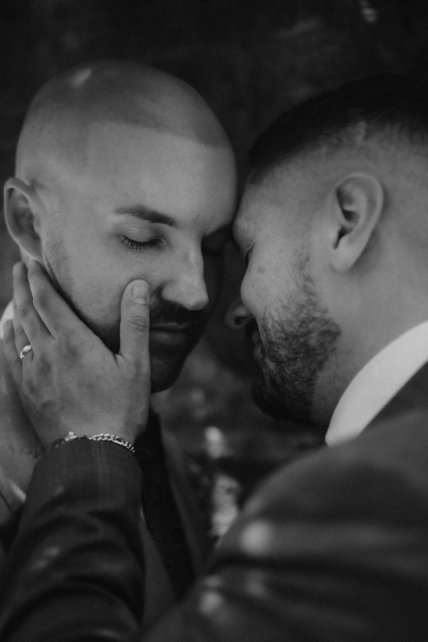 An intimate black and white portrait of two people sharing a tender moment.