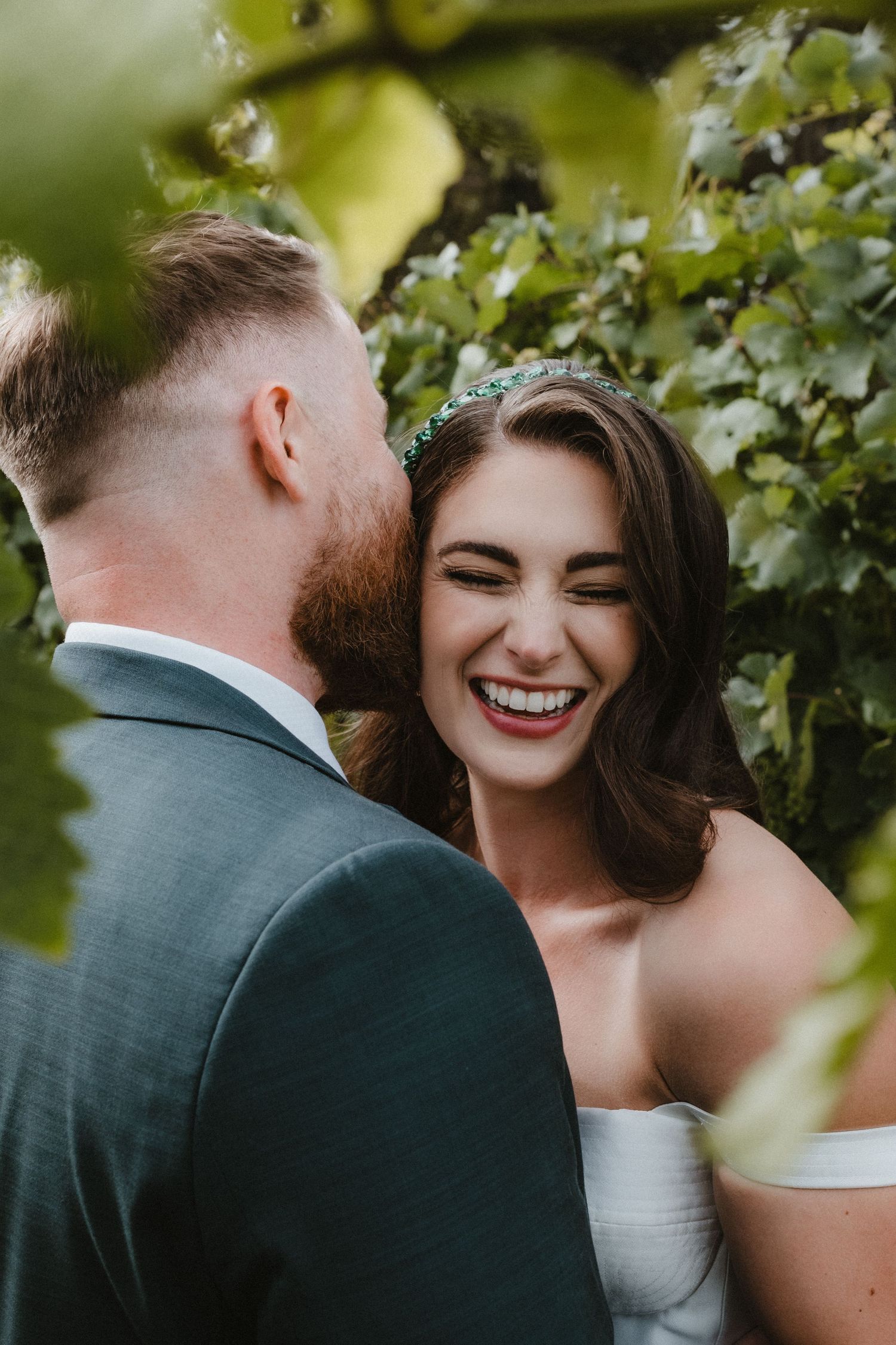 Romantic moment between couple among green vineyard leaves on their wedding day.