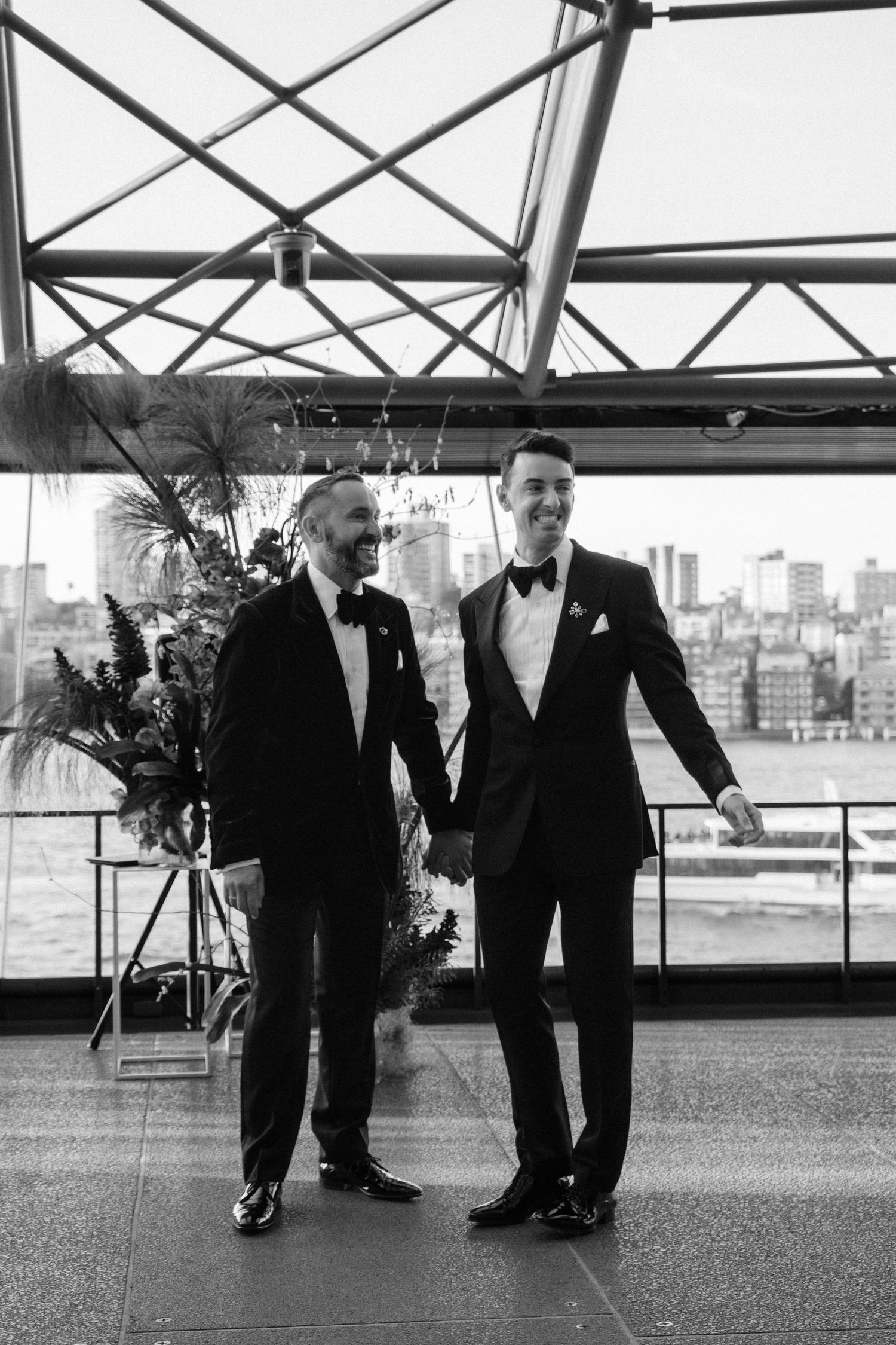 Black and white series of two people in formal attire walking and posing together in an industrial space.