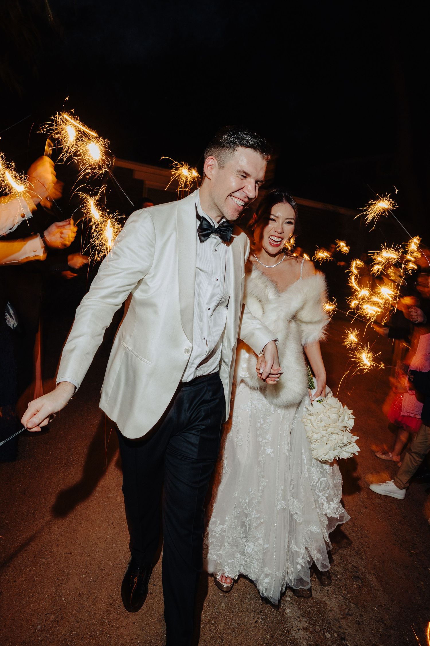 Couple dances with sparklers during nighttime wedding celebration.