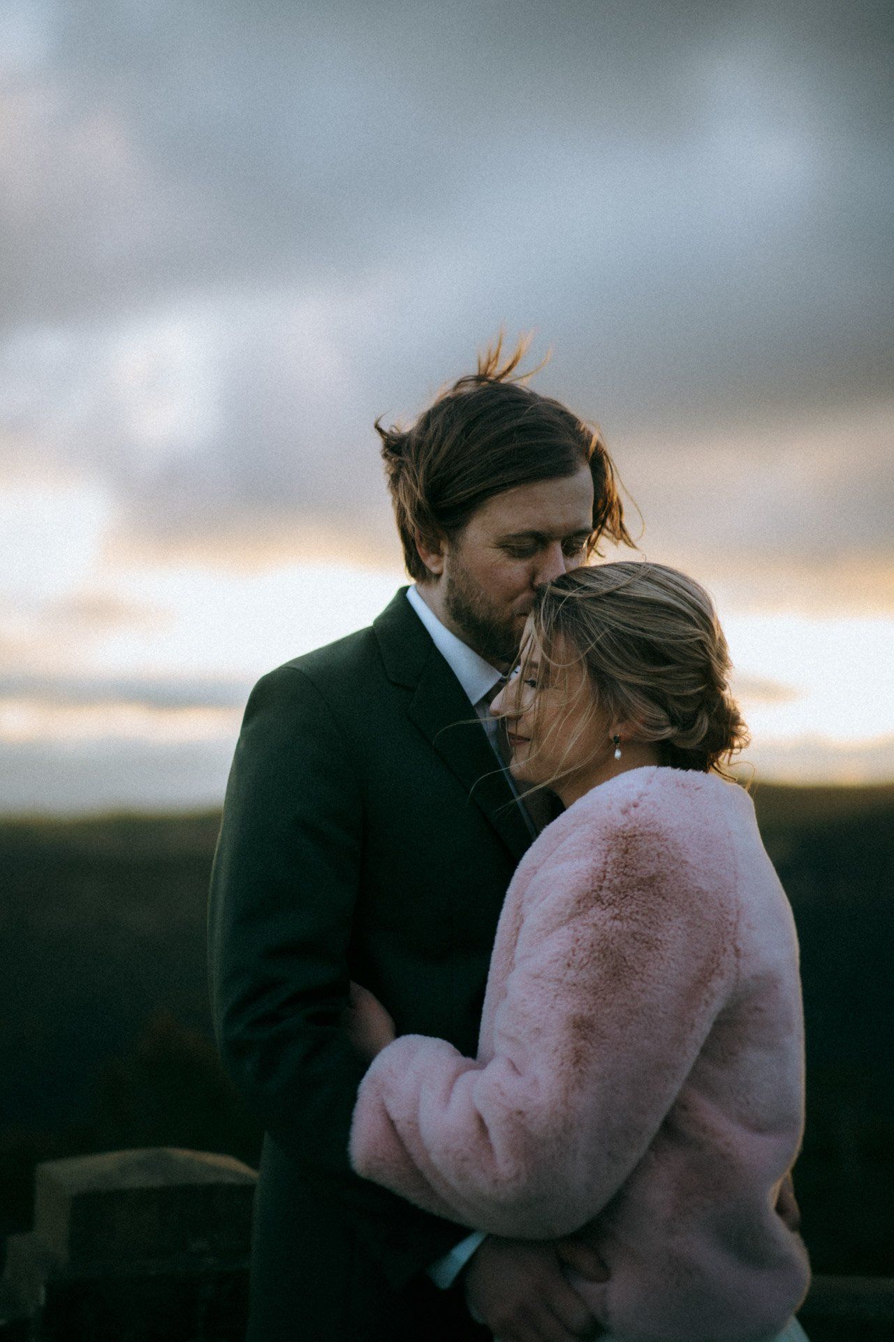 Romantic couple embracing at sunset in a tender outdoor moment.