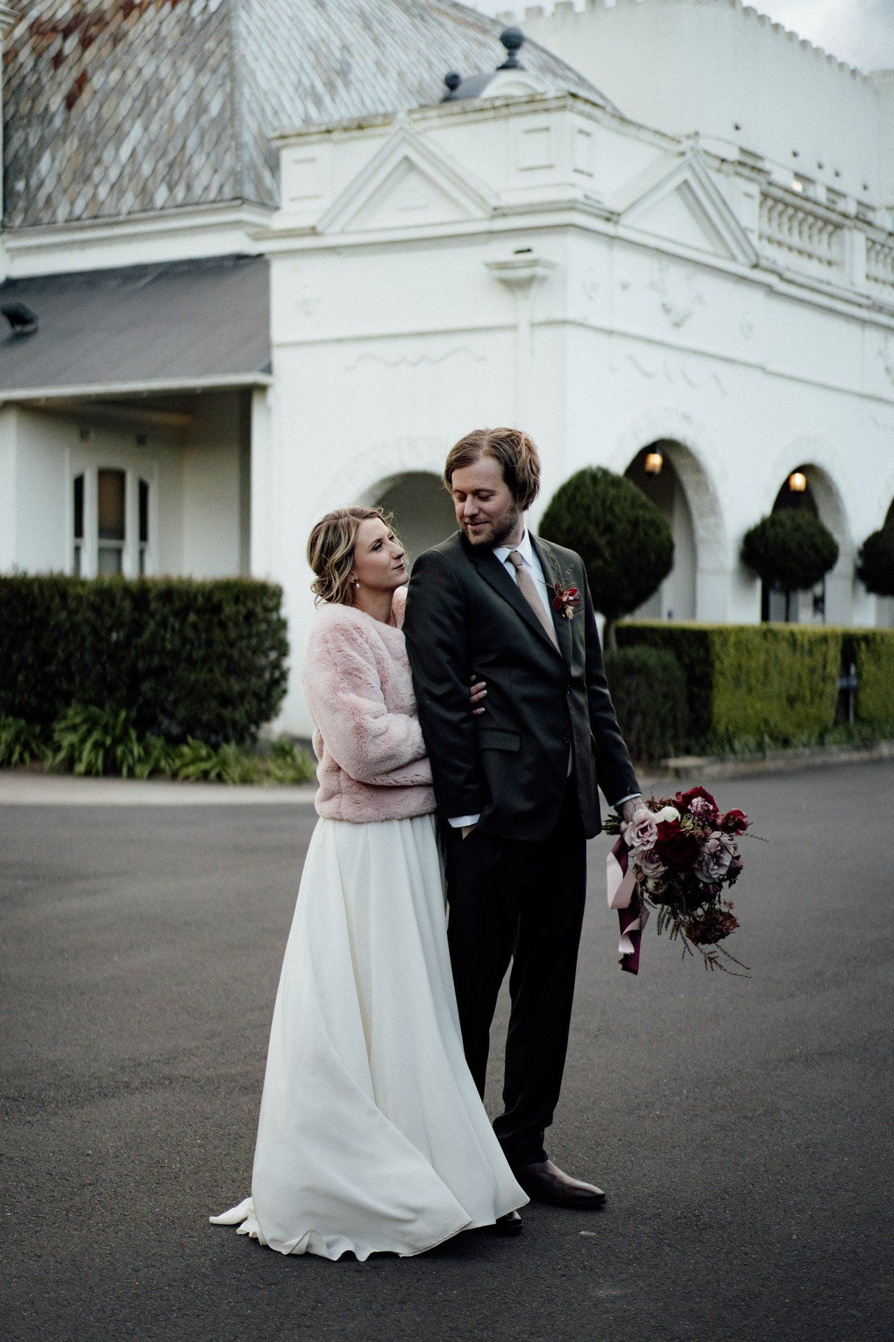 Wedding couple shares playful moments outside a white church building.