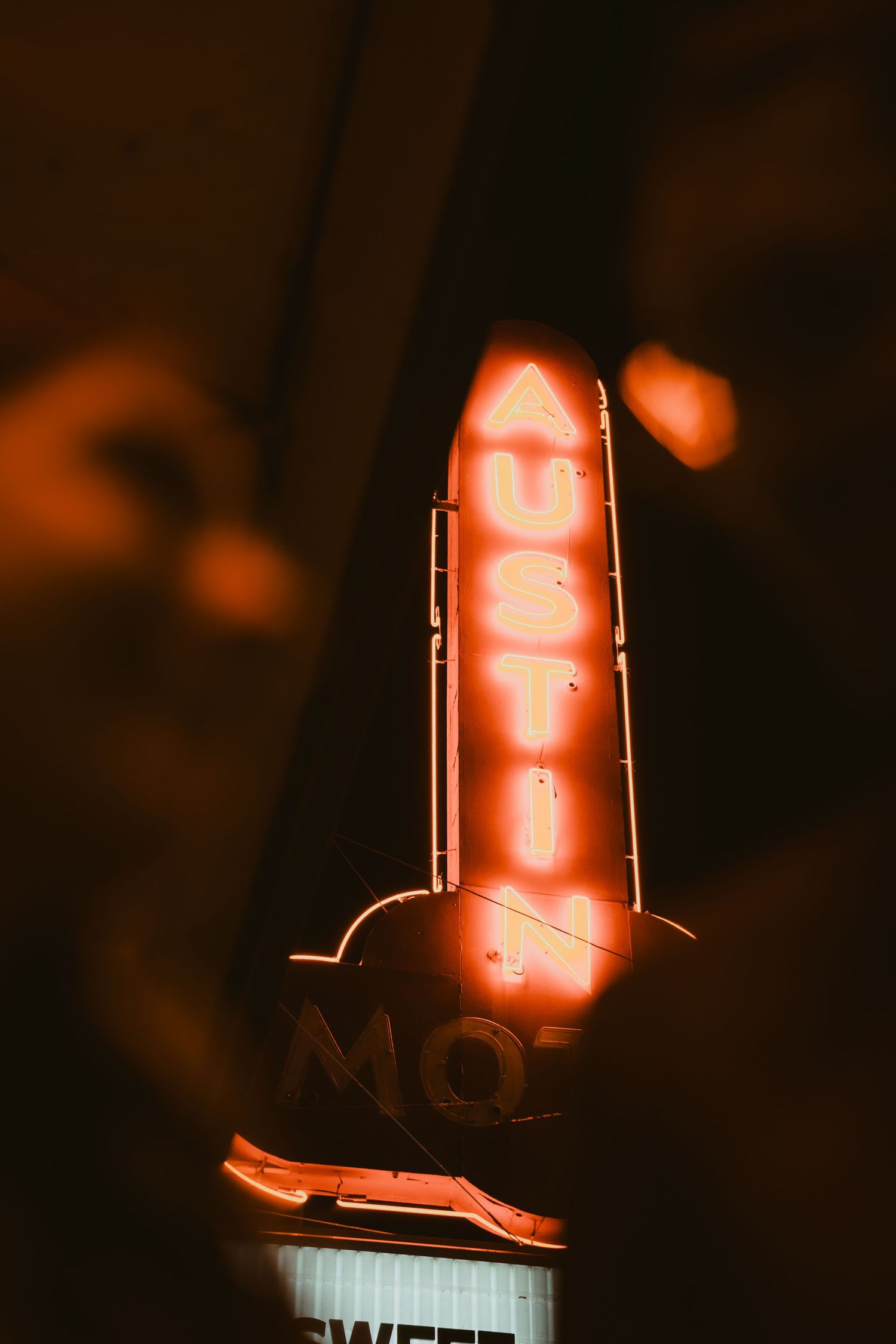 An illuminated vintage motel sign glowing red against a dark night sky.