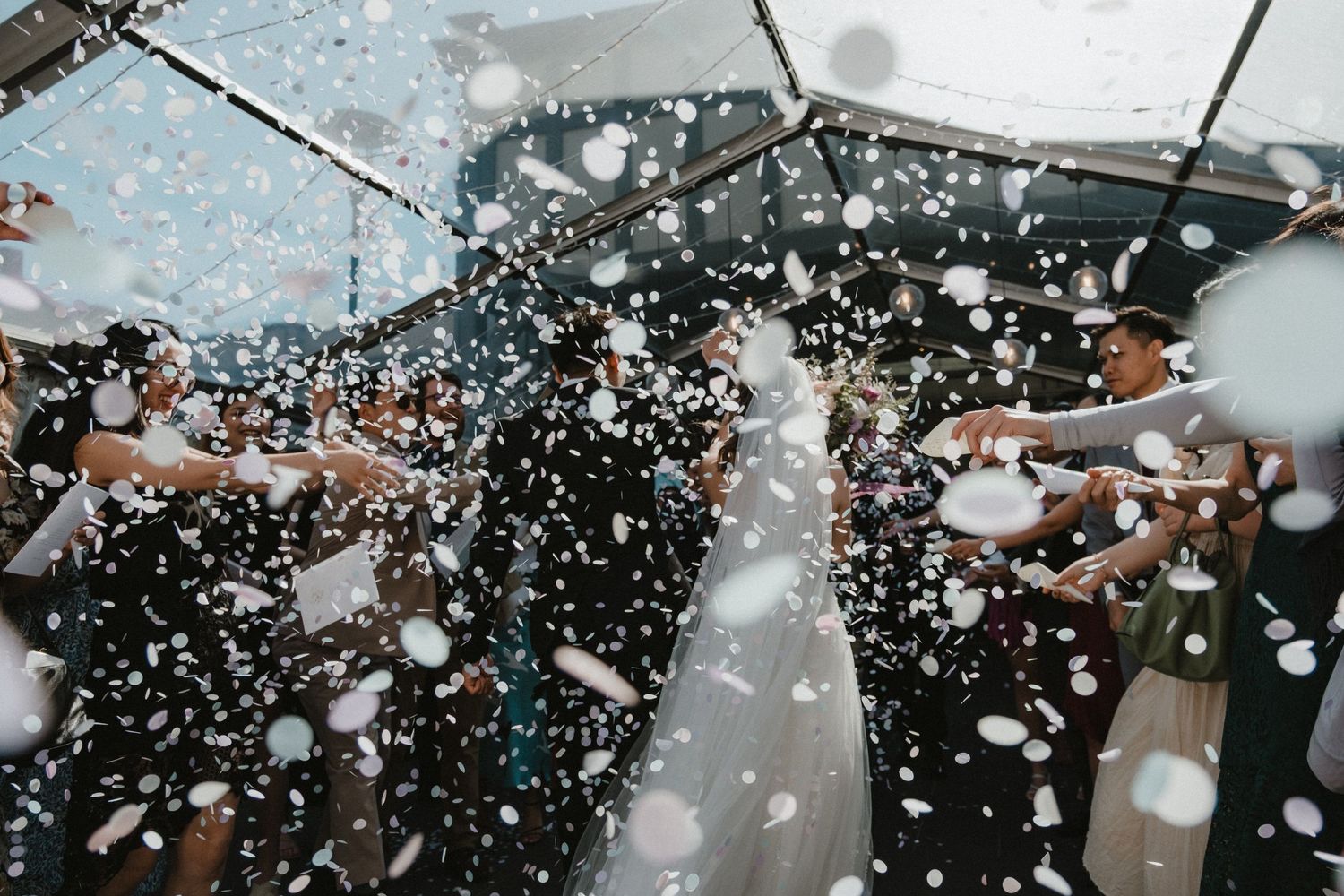 Celebratory moment with confetti falling during an outdoor wedding ceremony.
