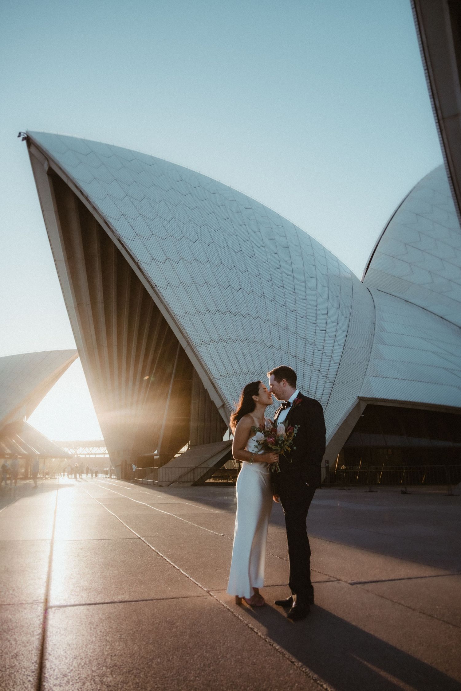 Wedding portraits at the Sydney Opera House with iconic white sail architecture at sunset.