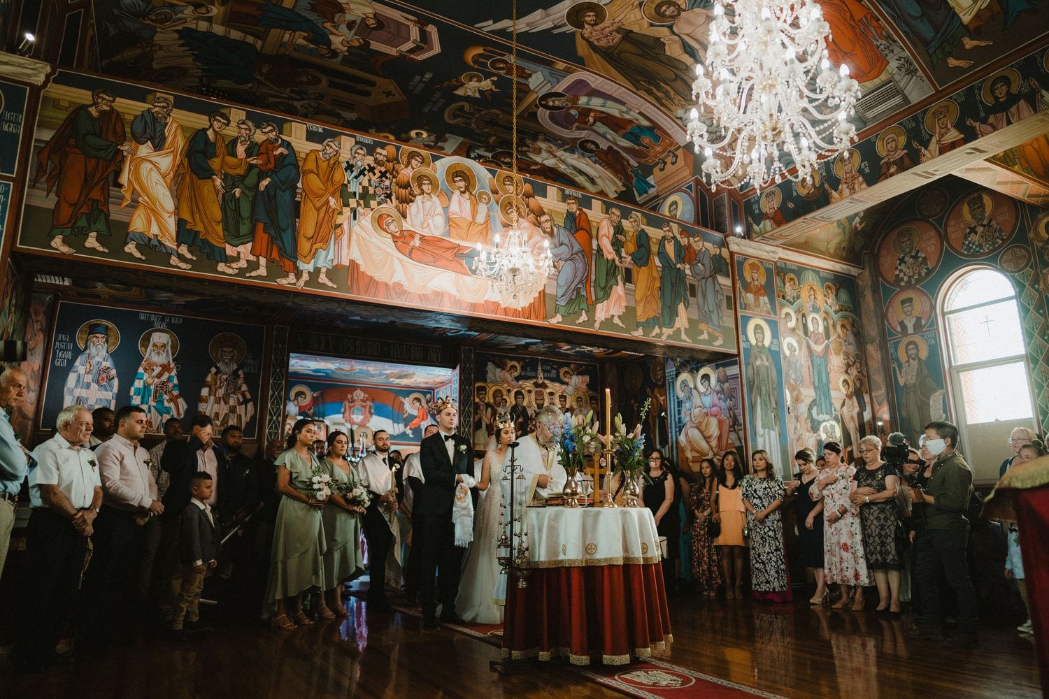 Ornate ballroom with vintage chandeliers and painted ceiling creates dramatic wedding reception atmosphere.