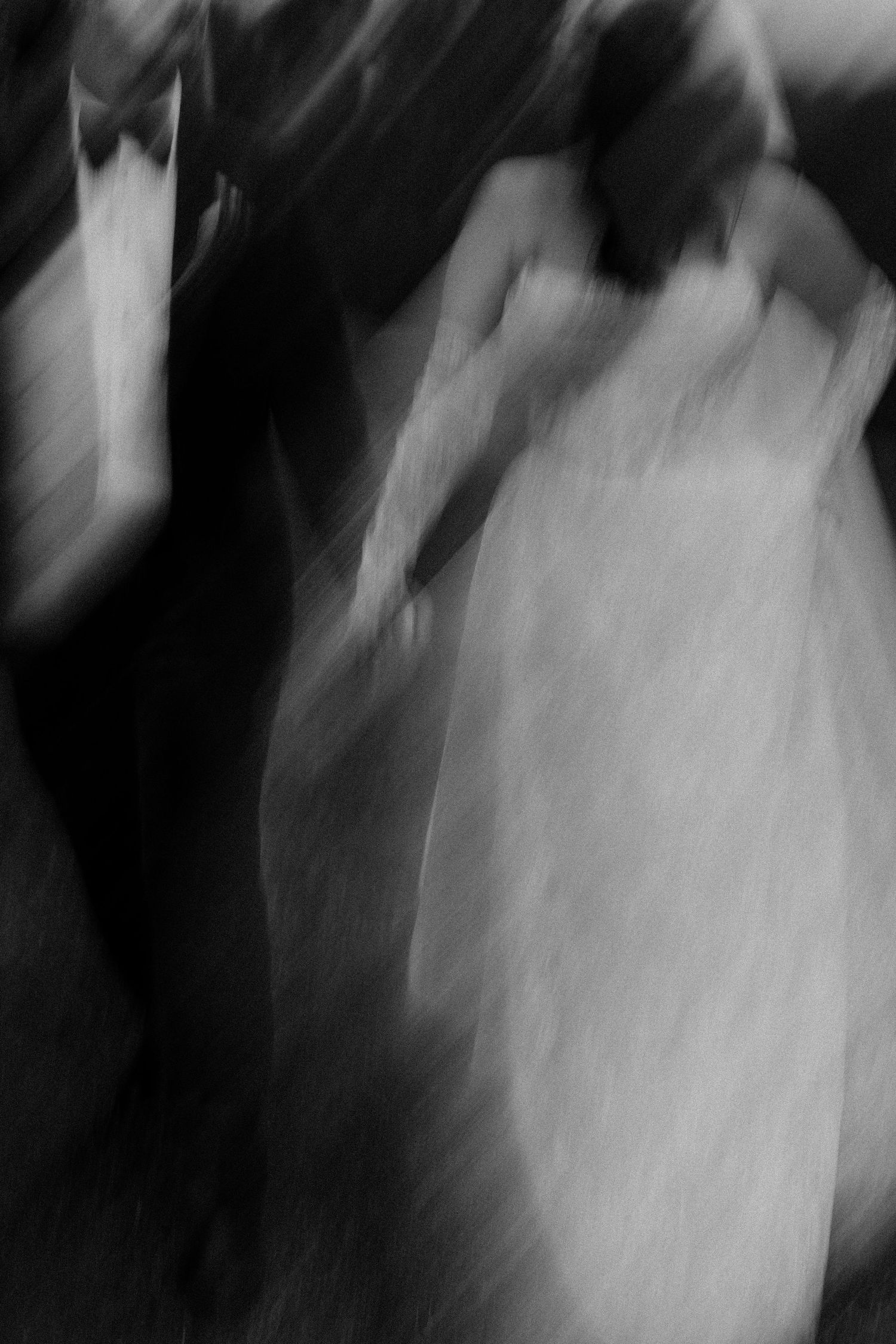 Blurred black and white photo of a bride and groom dancing at their wedding reception.