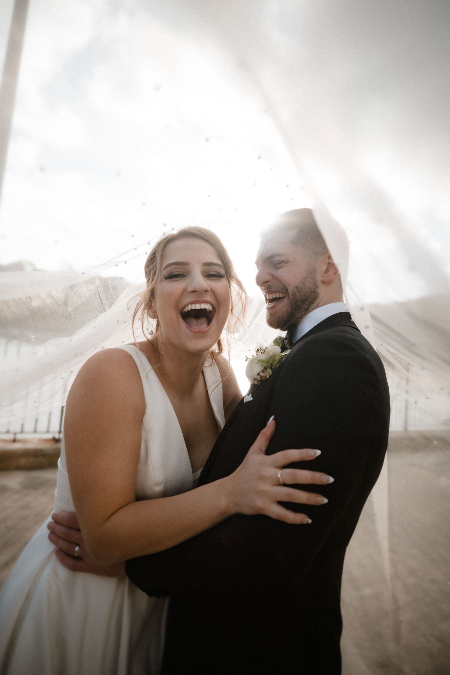 Happy couple sharing joyful laughter and embraces during their wedding photoshoot.