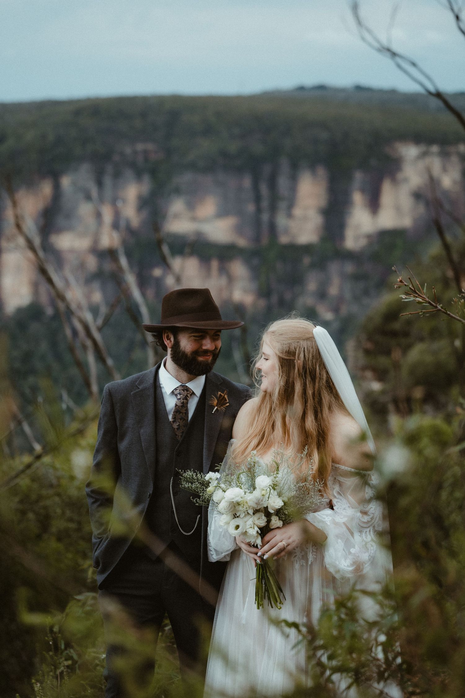 A romantic wedding photo session against dramatic mountain cliffs and natural scenery.