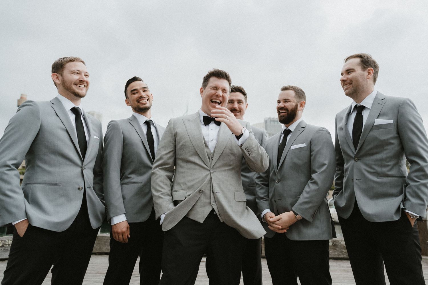 Groomsmen in matching gray suits share a candid moment together.