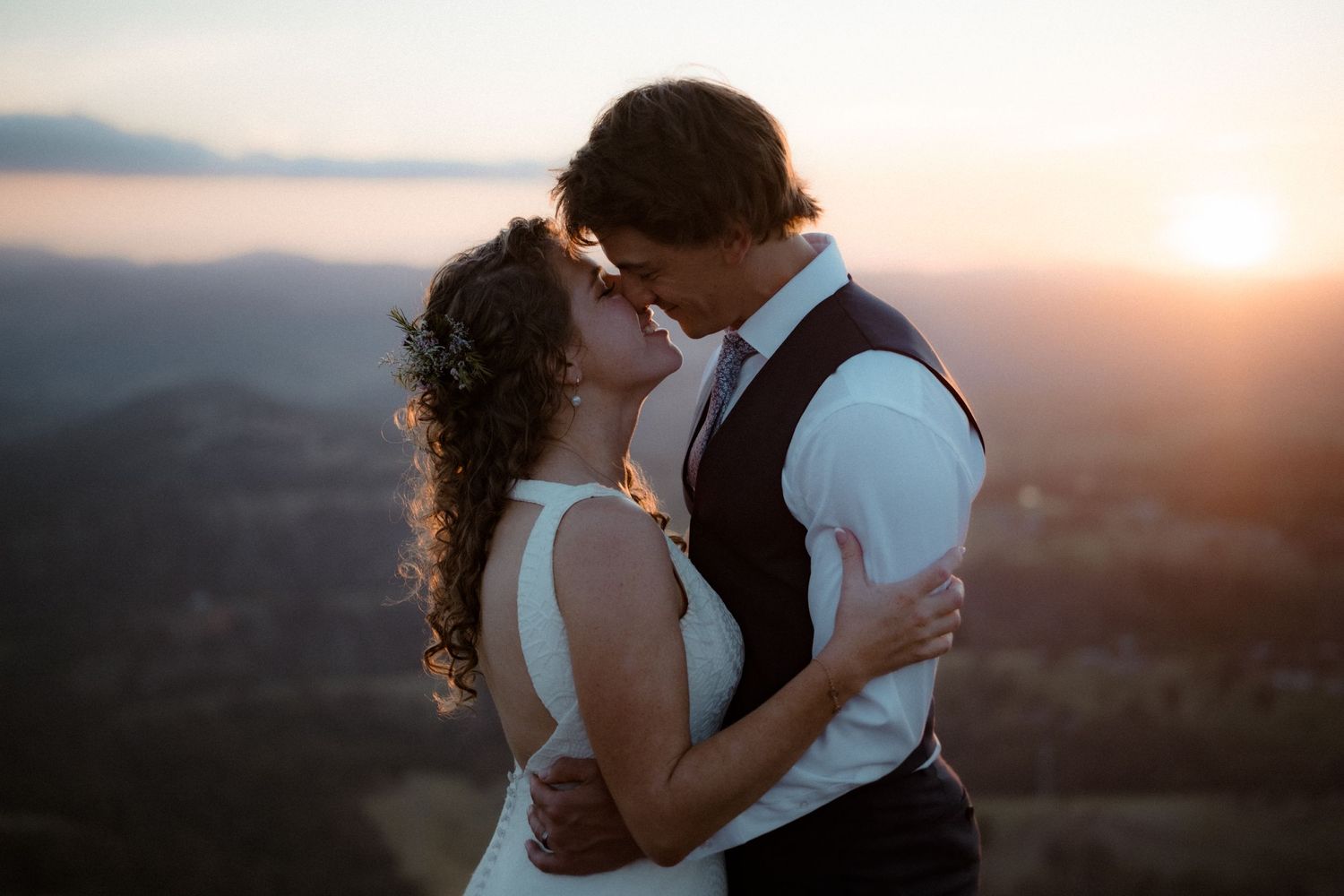 Romantic sunset silhouette of couple embracing against mountain landscape.