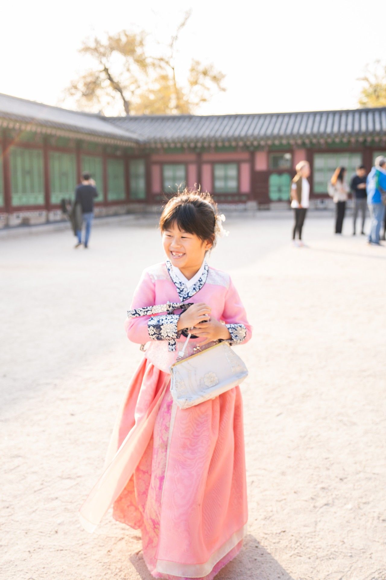 A person wearing a traditional pink Korean hanbok dress spins playfully in a historic courtyard setting.
