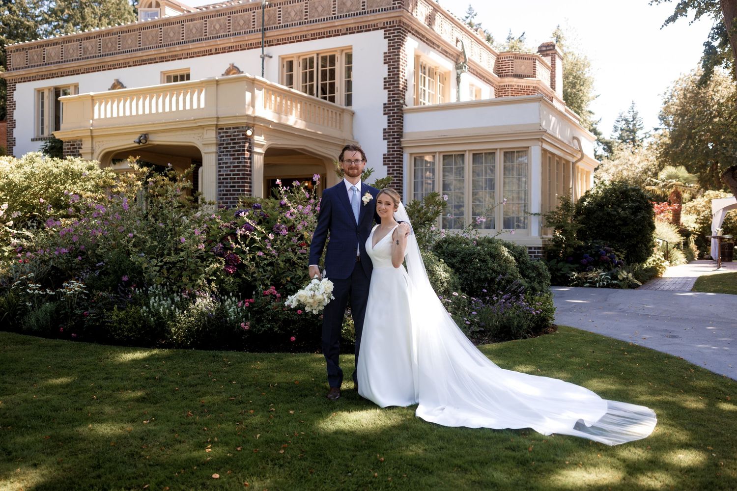 Elegant wedding photos taken outside a grand historic mansion with white columns and beautiful landscaping.