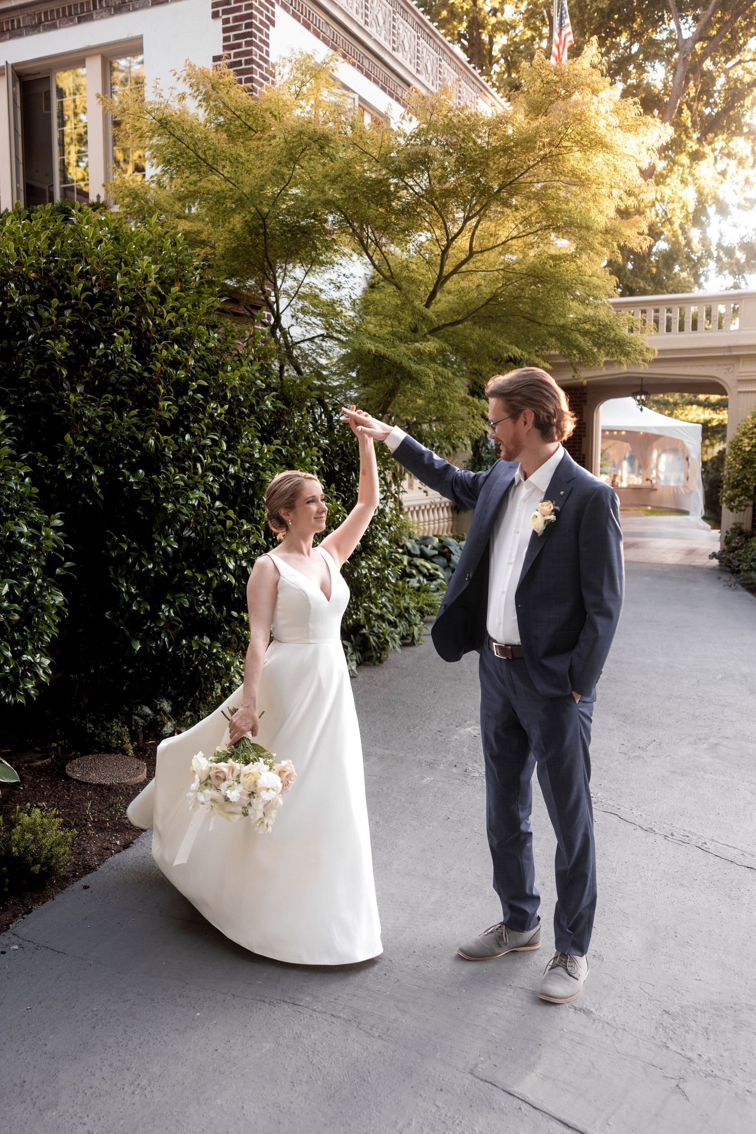 A couple performs a playful dance sequence on a paved walkway during their wedding.