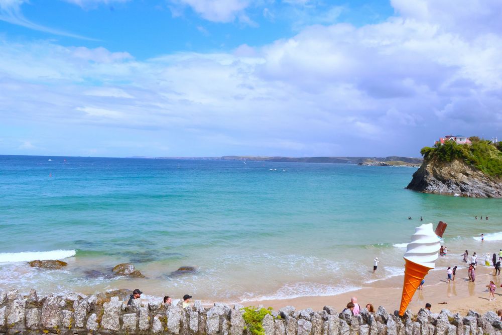 Full color photo of the ocean in Newquay, England with a large plastic ice cream cone in the foreground