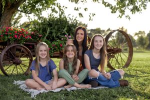 Relaxed group portrait in garden setting with decorative wagon wheel and greenery.