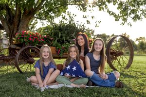 Casual summer portrait of group lying on blanket with vintage farm equipment in background.